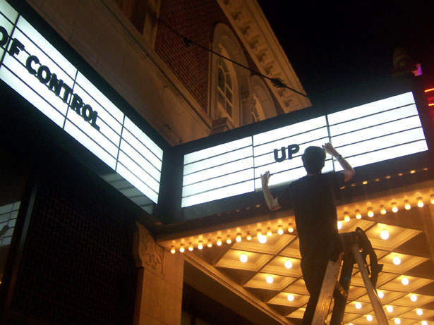 The Grandin Theatre's general manager, Jason Garnett, fixes a fluorescent in the marquee one summer Saturday night.