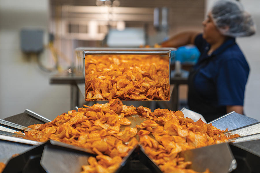 Freshly hand-seasoned, still-warm chips distribute across a chip scale for weighing and bagging.