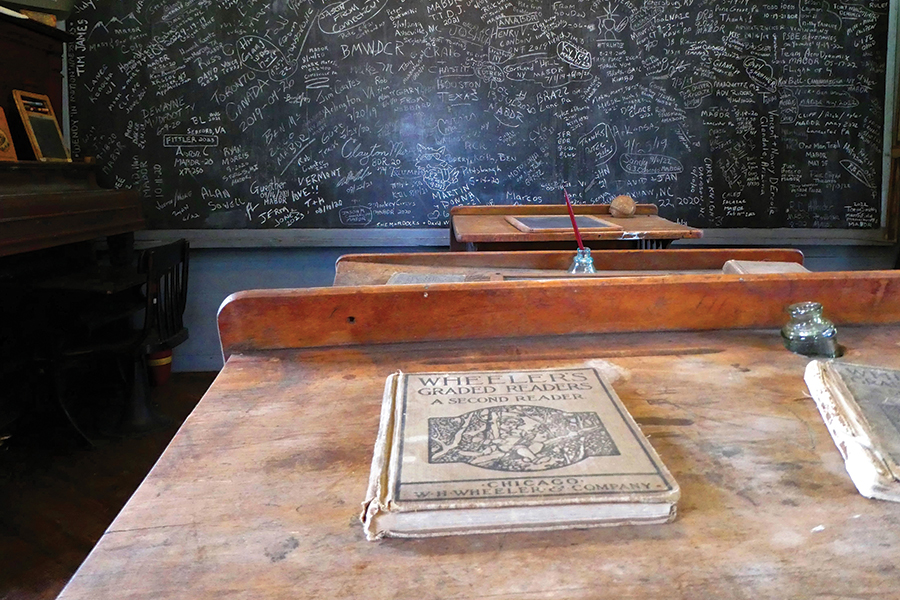 The three original desks at the Horn Camp School face the slate chalkboard which is scrawled with the signatures of visitors.