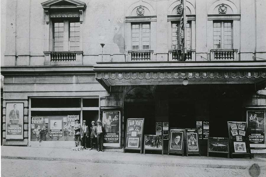 Staff and signs stand in front of the Academy, 1920s.