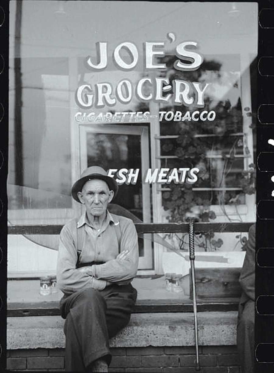 An unidentified man sits in front of Joe’s grocery store, Elkins, West Virginia, circa 1940s.
