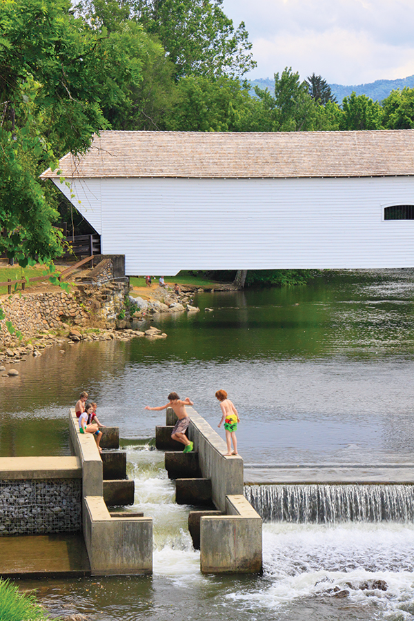 Children cool off on a hot summer day by jumping into the fish ladder of the weir dam on the Doe River just downstream of the Elizabethton Covered Bridge in Elizabethton, Tennessee.