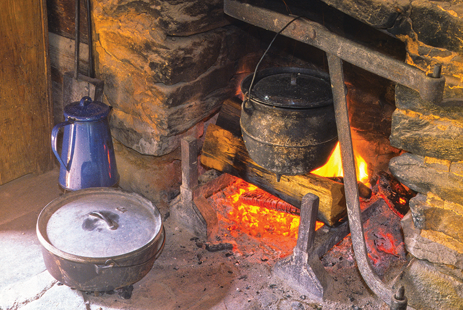 Cooking meals the old-fashioned way in the fireplace of the John Davis Cabin is demonstrated during Women’s Day at Oconaluftee Farm Museum in Great Smoky Mountains National Park.