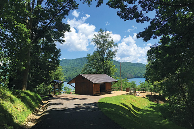 Fontana Dam Shelter (NC). A shelter sign says the famous “Fontana Hilton” was built by Mike Short and then donated by “Papa Smurff” in 1993. The large shelter sits above Fontana Lake, and is located near Fontana Dam. The shelter has two sets of double platforms inside and is one of only four (non-hut) shelters on the A.T. that sleeps more than 20 people. There are bathrooms with water, flushing toilets, and showers nearby, and there are also showers available at the dam. The only shelter with a large USB-charging station outside, it is also the lowest-elevation shelter in North Carolina.
