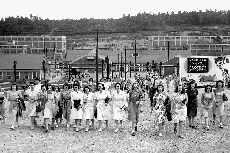These women workers leaving Y-12 were photographed by Ed Westcott, famous Manhattan Project photographer; and the lady on the extreme left with her coat draped over her arm was “Miss Atomic Bomb” in 1945.