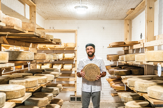 Cheesemaker Crosby Jack holds a wheel of cheese at Looking Glass Creamery in Columbus, a stop along the Western North Carolina Cheese Trail.