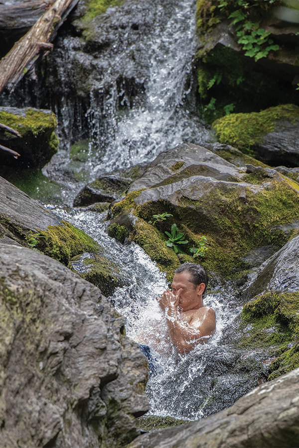 A visitor cools off in a section off Catawba Falls near Old Fort, North Carolina. Over 100 feet  high, the waterfall is divided into three main sections and is accessible by an easy walk.