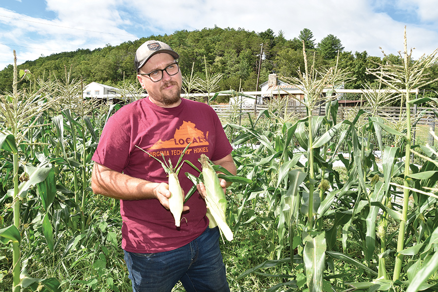 Trevor Saville contrasts corn grown normally (left ear) with some grown in a sustainable fashion through his drip irrigation method (right ear).
