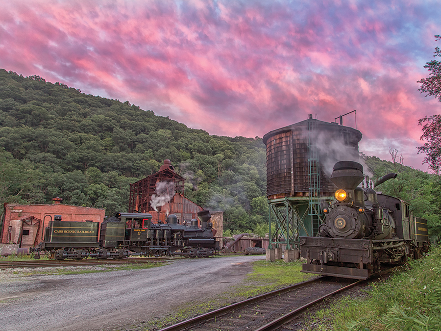 Two of West Virginia’s Cass Scenic Railroad State Park’s Shay steam locomotives sit by the water tower at sunset.