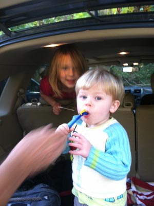 Grayson tries to master the water bladder at the end of the hike as Lily smiles at having done the walk.