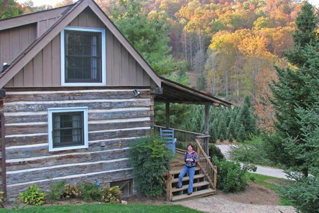 Elaine Roberts stands outside the Cosby Cabin, moved to the property from Cosby, Tenn. in 1997.