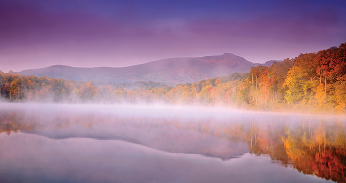 Price Lake, at Milepost 297 of the North Carolina Blue Ridge Parkway, reflects perfectly the profile of Grandfather. Photographer Brent McGuirt had waited several fall mornings for the mountain and the fog to coalesce for this shot, as the golden light struck the face of Grandfather Mountain and a cool morning mist hovered over the lake.