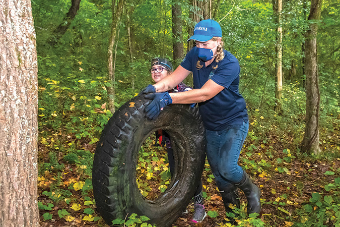 Kathleen Gibi and a young volunteer roll a semi tire to the boat at a Keep the Tennessee River Watershed Beautiful Month cleanup on Nickajack Lake of the Tennessee River near Chattanooga.
