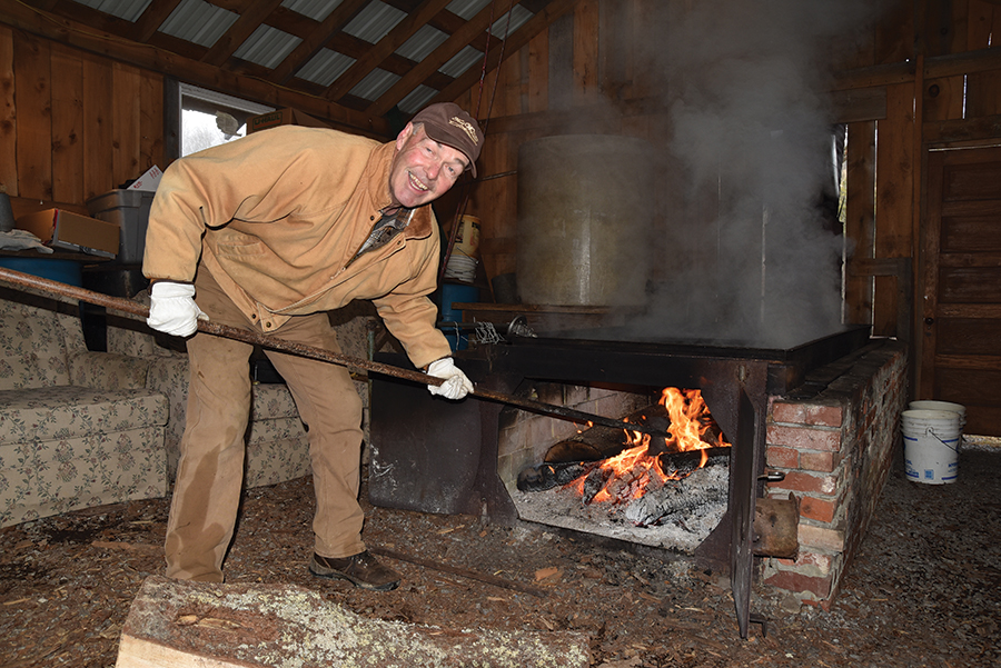 Black locust is the preferred wood for creating maple syrup, according to Bob Sheets. Here, he positions a slab of wood inside the brick arch.