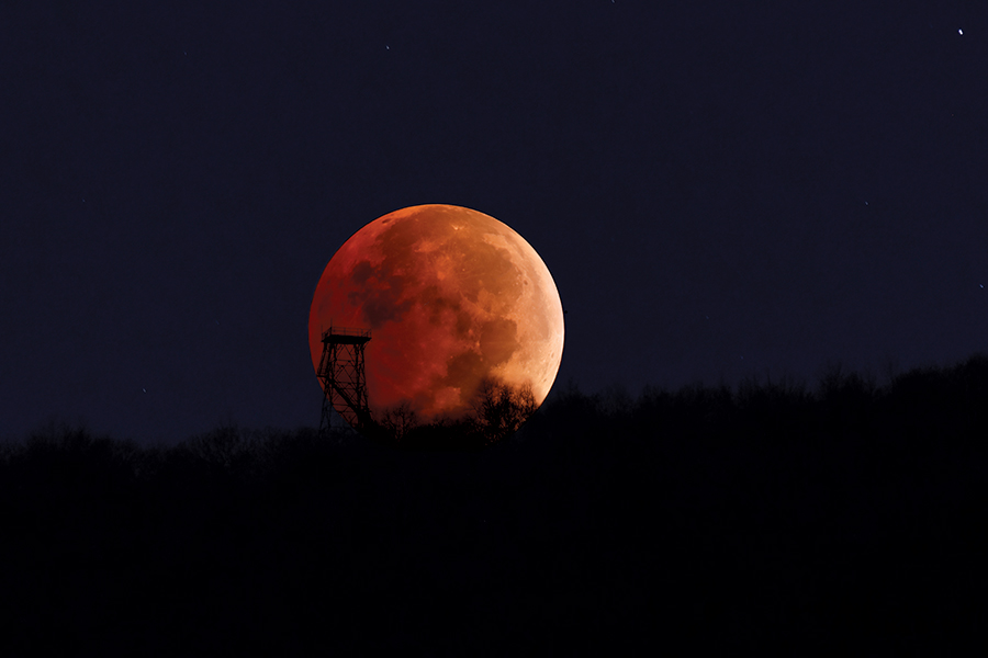 The total eclipsed moon sets behind the Holston Mountain fire tower in Carter County.