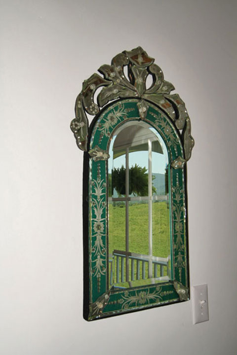 An antique mirror reflects the scenic landscape outside the front door.