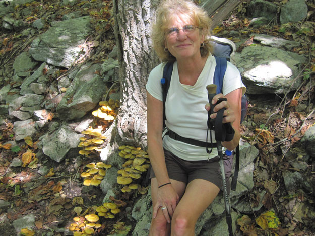 The Greatest Day Hiker Of Them All, no doubt hoping the pretty yellow mushrooms draw attention from her wind-blown hair.