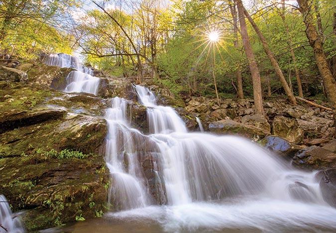 The sun peeks at the cascading falls of Dark Hollow in Shenandoah National Park, Virginia.