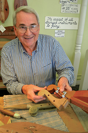 The hand-made dulcimers of Warren May make music around the world. He shows the scroll section in different stages of completion.