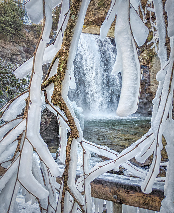 View of Looking Glass Falls, near Brevard and the Blue Ridge Parkway, is taken from behind ice-coated branches. From the photographer: “There were several photographers already there, and to their amusement, I sat down on the top step carrying my tripod, with the camera attached, and then slid down, one step at a  time, on the seat of my pants to get this shot on an ICE day!”