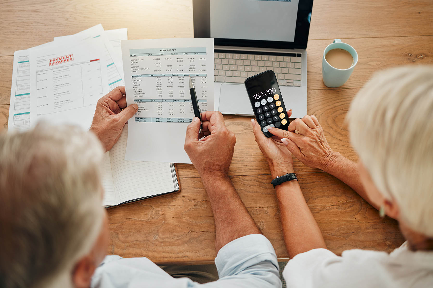Home budget, finance planning and senior couple calculating their expenses, bills or income during retirement with a calculator, laptop and paper documents from behind. Man and woman discuss savings.