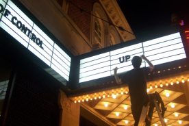 The Grandin Theatre's general manager, Jason Garnett, fixes a fluorescent in the marquee one summer Saturday night.