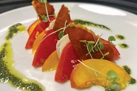 Local tomatoes, peaches, fresh mozzarella, prosciutto and basil make up a summertime salad at 1010 Bridge.