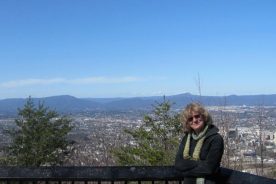 The Greatest Day Hiker Of Them All on the lower overlook atop Mill Mountain, with downtown to the right and the McAfee profile just above her head.