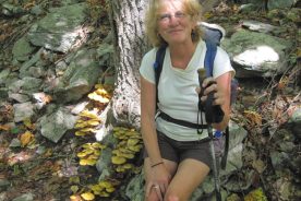 The Greatest Day Hiker Of Them All, no doubt hoping the pretty yellow mushrooms draw attention from her wind-blown hair.
