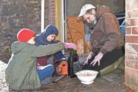 Eli, Sam and Granddad prepare the chainsaw for a morning in the woods.
