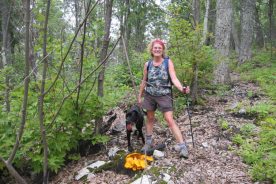 The Greatest Day Hiker Of Them All with black dog and orange mushrooms, and taking a respite from chigger dismay.